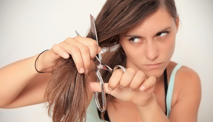 девушка отрезает ножницами свои волосы