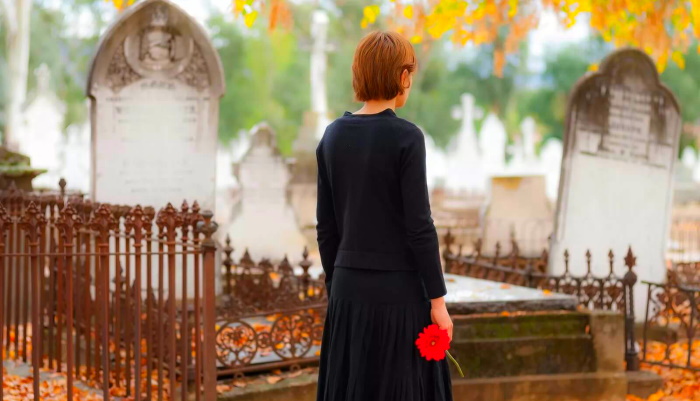 девушка с красным цветком стоит у могил