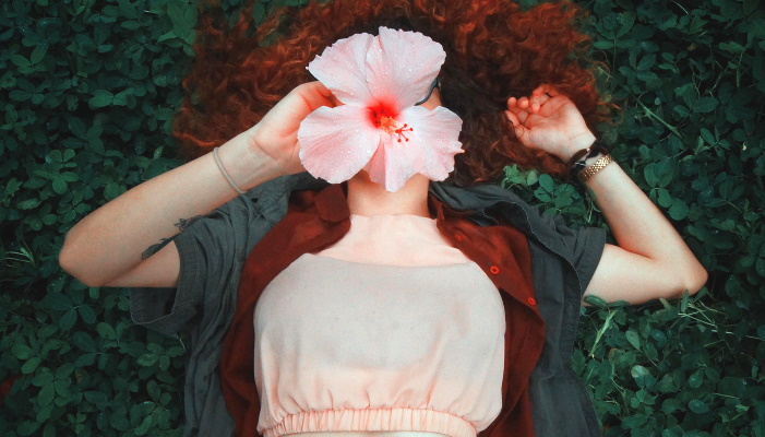 девушка лежит с цветком на лице