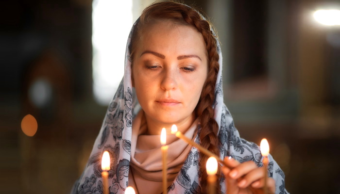 девушка ставит свечу в храме